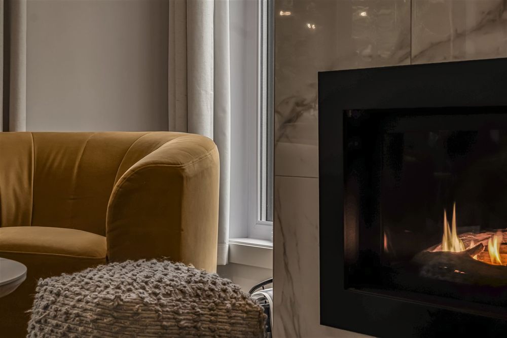 Fauteuil en velours moutarde près d'un foyer en marbre