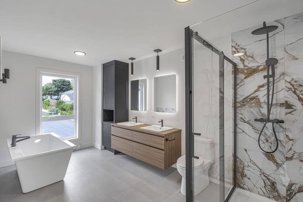 Salle de bain principale d'une maison neuve : bain autoportant, vanité double et douche en marbre